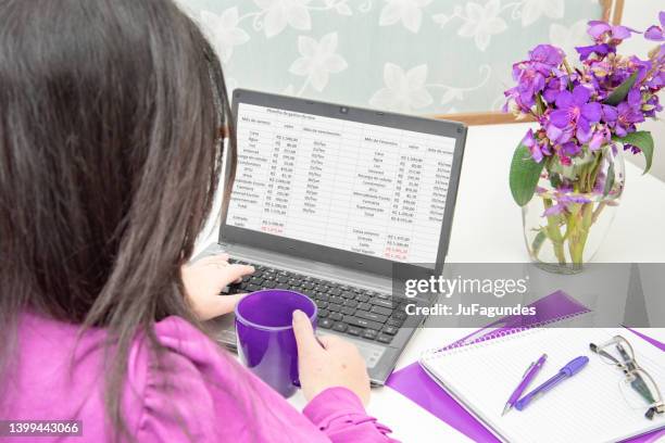 woman sitting at table with notebook with personal finance worksheet - kalkylblad bildbanksfoton och bilder