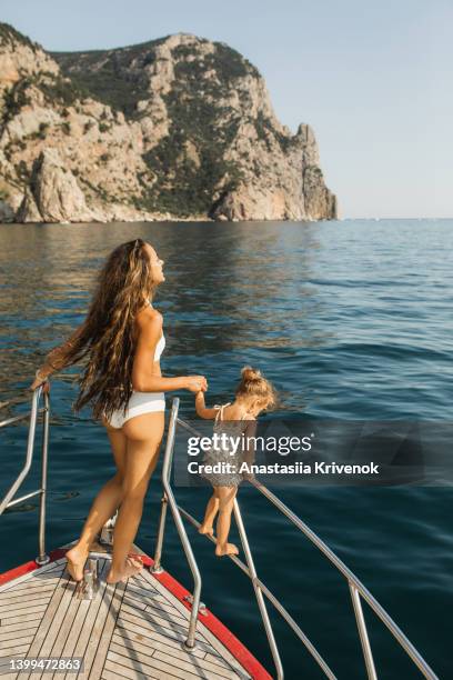 little girl and mother enjoying nature on a yacht. - baby boot stock-fotos und bilder