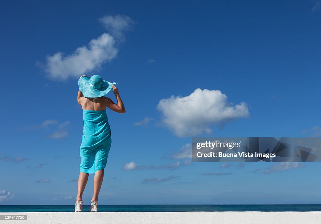 Woman with blue scarf and hat on a beach