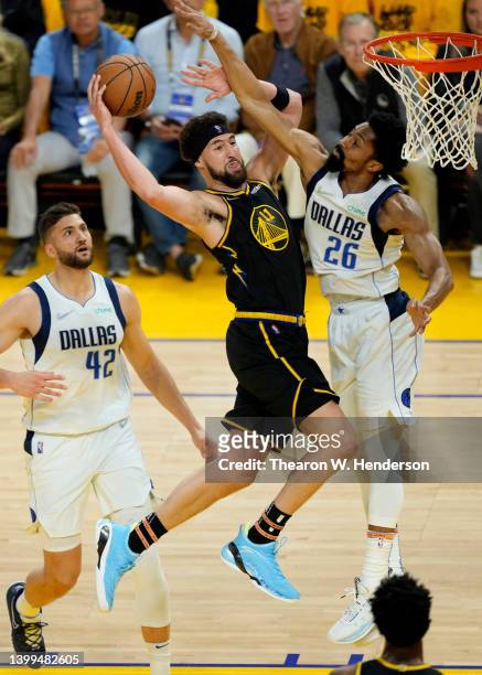 Klay Thompson of the Golden State Warriors drives to the basket against Maxi Kleber and Spencer Dinwiddie of the Dallas Mavericks during the first...