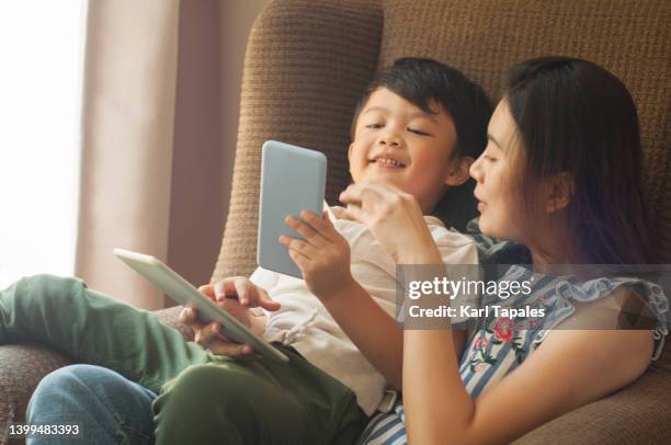 southeast asian mother and son are using digital tablet and smart phone for leisure at home - philippines family 個照片及圖片檔
