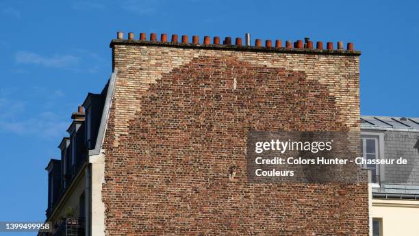 weathered brick wall with an alignment of terracotta pots and skylights and blue sky in paris - dachgiebel stock-fotos und bilder