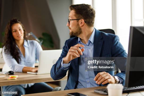businessman turning around, looking over shoulder when his coworker is asking for work advice - looking over shoulder stock pictures, royalty-free photos & images