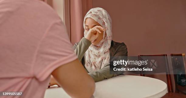 two women holding hands at a cafe. muslim friends showing love, support and affection while sitting at a restaurant table - middle east friends stock pictures, royalty-free photos & images