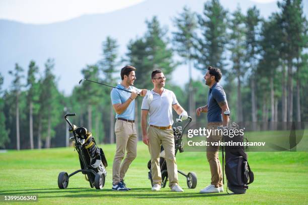 grupo de amigos golfistas masculinos, jugando al golf en un hermoso día soleado, hablando y sonriendo mientras está de pie en el campo de golf - golf fotografías e imágenes de stock