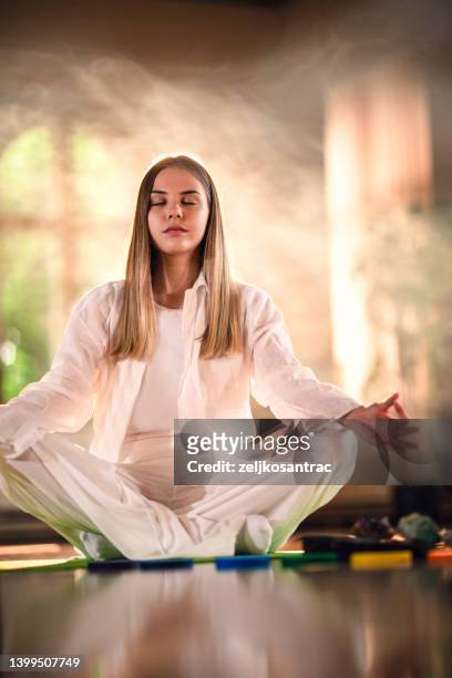 peaceful girl sitting in lotus pose and meditating with closed eyes - namaste stock pictures, royalty-free photos & images