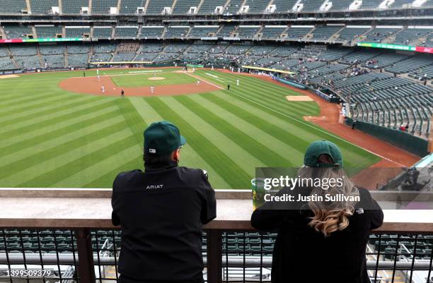 Two baseball fans watch the Oakland Athletics play the Texas Rangers in front of a small crowd at RingCentral Coliseum on May 26, 2022 in Oakland,...