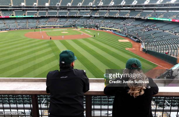Two baseball fans watch the Oakland Athletics play the Texas Rangers in front of a small crowd at RingCentral Coliseum on May 26, 2022 in Oakland,...
