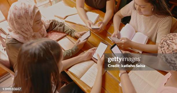 a group of young women using their phones at a book club meeting in a cafe a cafe. a study group working together online with their smartphones - reading books club stockfoto's en -beelden