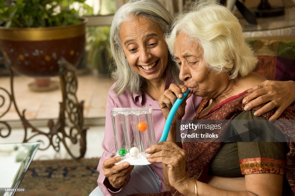 Woman surprised on old friend using spirometer to stimulate lung