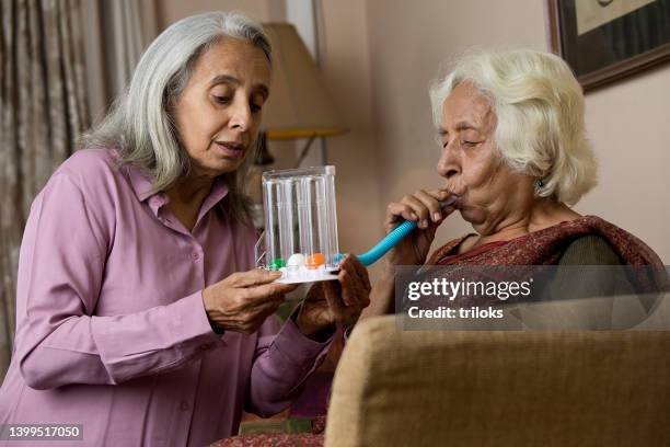 elderly woman supporting her female friend after using a spirometer to stimulate lung - copd stock pictures, royalty-free photos & images