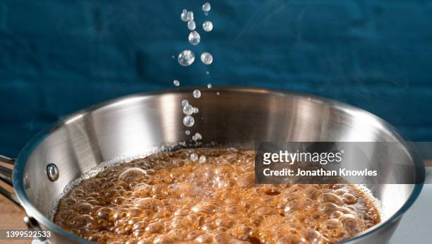 triple sec falling into caramelized sauce in hot pan - iron bowl stock pictures, royalty-free photos & images