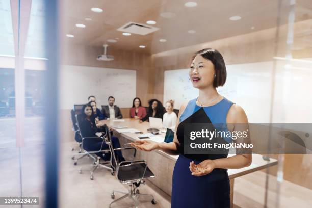 mature korean ethnicity asian businesswoman leads colleagues in a meeting conference in business office discussion presentation - presentation materials stock pictures, royalty-free photos & images