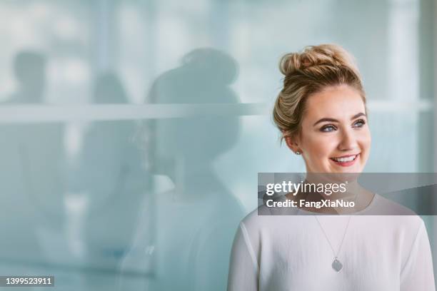 portrait of caucasian young woman looking forward in modern office space - portrait solid stock pictures, royalty-free photos & images
