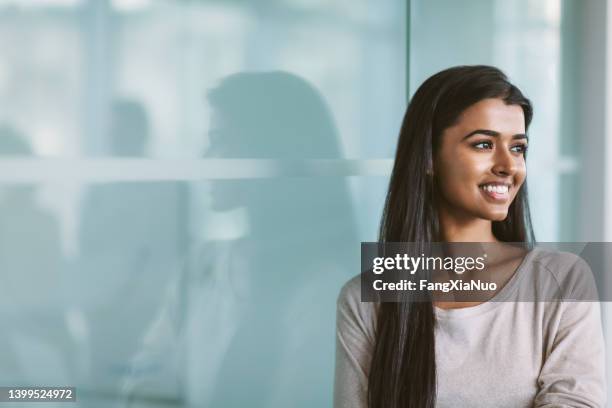 portrait of indian ethnicity asian young woman looking forward in modern office space - portrait solid stock pictures, royalty-free photos & images