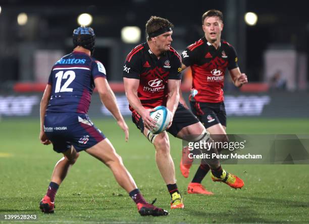 Scott Barrett from the Crusaders looks to offload while under pressure from 12. Hamish Stewart from the Reds during the round 15 Super Rugby Pacific...