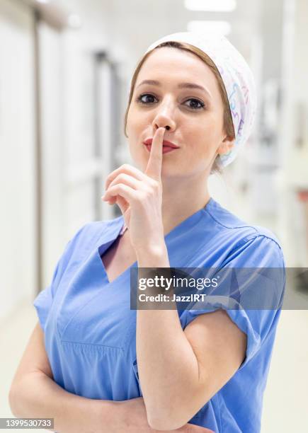 oung enfermeira mulher para ficar quieto com o dedo nos lábios. silêncio e conceito secreto - silêncio - fotografias e filmes do acervo