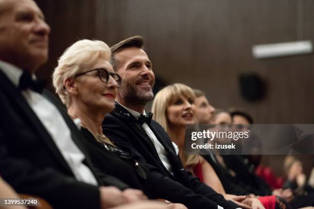 smiling spectators sitting in the theater - theater gala stock pictures, royalty-free photos & images