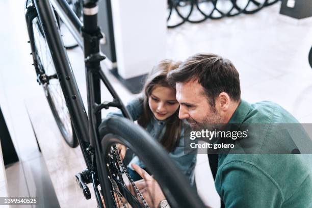 man and daughter checking out new bike in bike shop - buying a bike bildbanksfoton och bilder