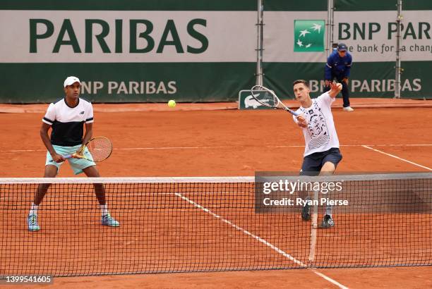 Joe Salisbury of Great Britain plays a forehand as partner Rajeev Ram of the United States looks on during their match against Miomir Kecmanovic of...