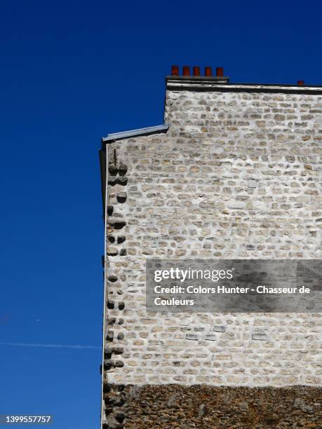 close-up of the white and natural stone gable of a parisian building with chimney and blue sky - dachgiebel stock-fotos und bilder