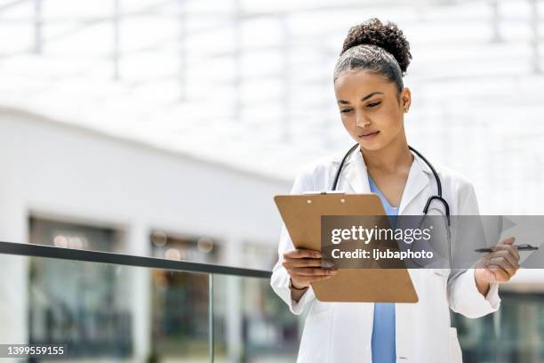female doctor holding clipboard - prancheta imagens e fotografias de stock