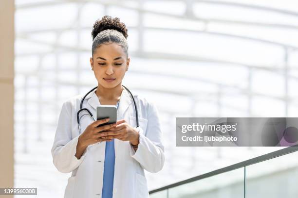 managing her daily medical duties - doctor using phone stock pictures, royalty-free photos & images