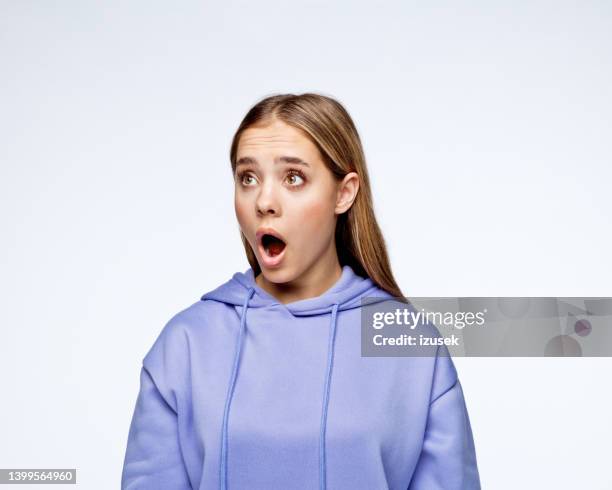 surprised teenage girl in lilac hoodie - teen disbelief stock pictures, royalty-free photos & images