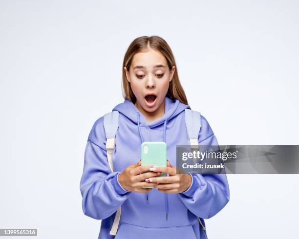 surprised teenage girl wearing lilac hoodie - happy teenagers phone stock pictures, royalty-free photos & images