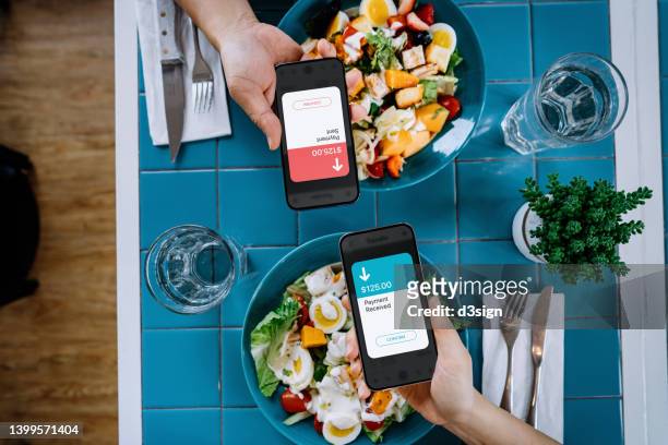 table top view of friends splitting bill, sending / receiving payment of the meal through digital wallet device on smartphone while dining together in restaurant. smart banking with technology - sending payment stock pictures, royalty-free photos & images