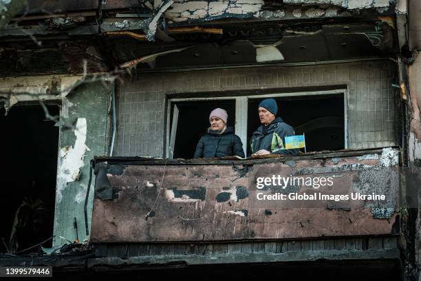 Local residents stand on their damaged balcony in hit by shelling high-rise apartment building in the Obolonskyi District on March 14, 2022 in Kyiv,...