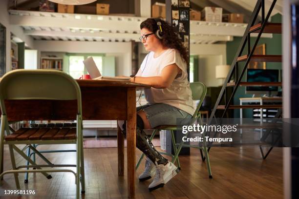 a woman working from home at the dining table. - amputee working stock pictures, royalty-free photos & images