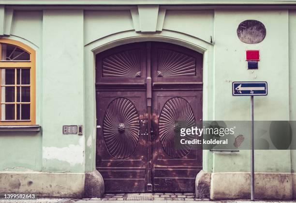 old heavy wooden double door with ornaments of historic building with green shabby walls - cechy stockfoto's en -beelden