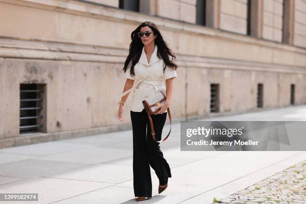 Leo Eberlin wearing Celine Triomphe canvas beige bag, Pinko navy blue pants, Sandro creme vest, & other stories shades and Gianvito Rossi brown...