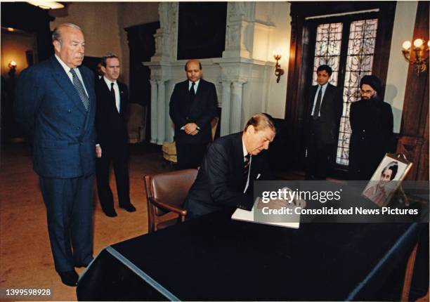 President Ronald Reagan signs a condolence book at the Embassy of India, Washington DC, October 31, 1984. Standing behind him are, from left, US...