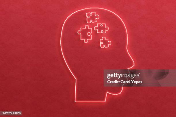 paper head with puzzle pieces-autism concept.in red neon lights - brain training stock-fotos und bilder
