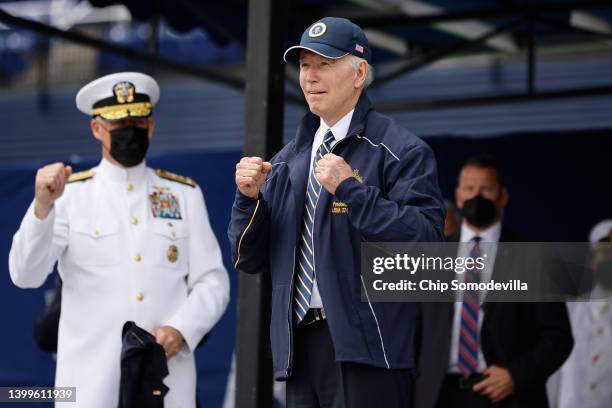 President Joe Biden shows off the jacket and hat he received as a gift from the graduating class of the U.S. Naval Academy at the conclusion of the...