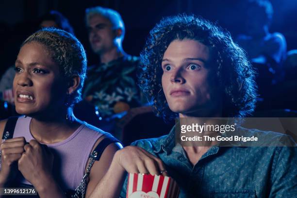 friends watching scary movie at movie theater - film screening stockfoto's en -beelden