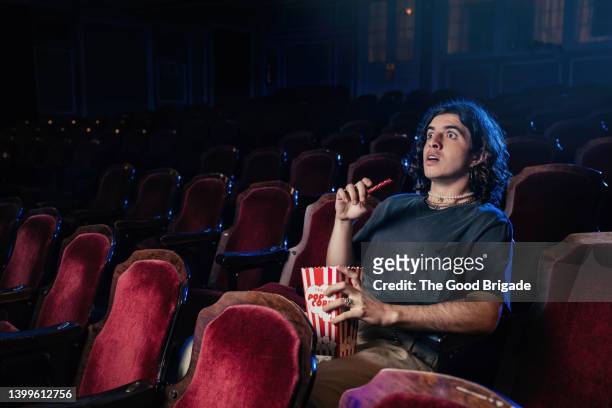 young man watching movie in theater alone - filmpremiere stock-fotos und bilder