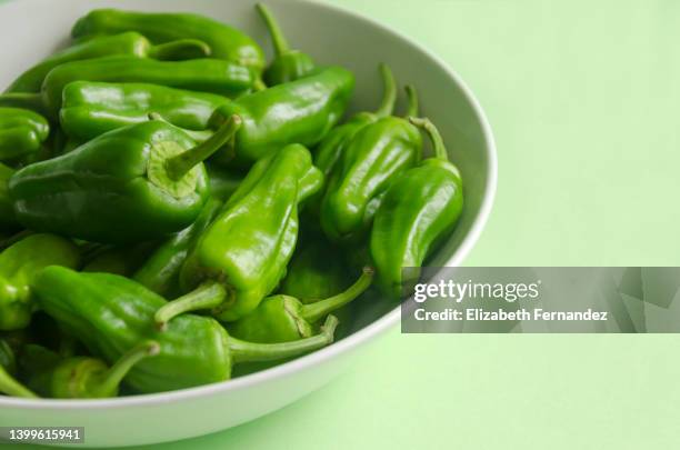 padron peppers on green background - pimientos stock-fotos und bilder