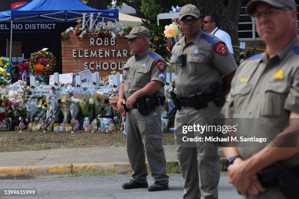 Texas Highway Patrol Troopers stand at attention in front of a memorial for the victims of the mass shooting at Robb Elementary School on May 27,...