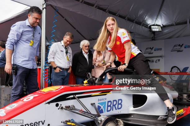 Driver Aurelia Nobels gets on her car as Bernie Ecclestone looks on during a visit to the Velocitta racetrack for a Stock Car and Formula 4 race on...