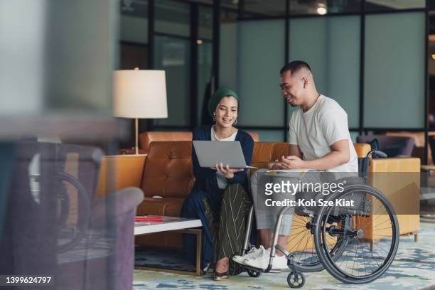 teamwork in business - a female leader sharing insights with a disabled co worker - rolstoel stockfoto's en -beelden
