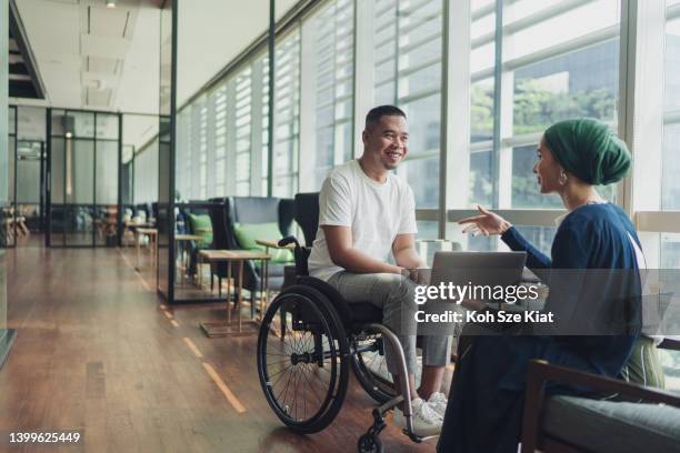 trabajo en equipo en los negocios: una mujer líder que comparte ideas con un compañero de trabajo discapacitado - discapacidades físicas o mentales fotografías e imágenes de stock
