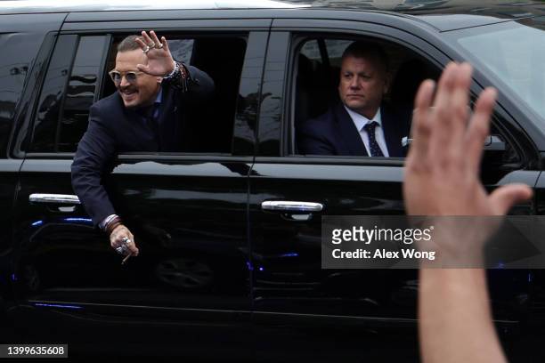 Actor Johnny Depp waves to supporters from his vehicle as he leaves a Fairfax County Courthouse May 27, 2022 in Fairfax, Virginia. Jury has started...