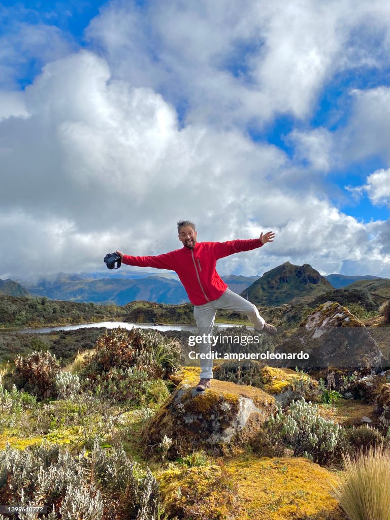 Young handsome latin male backpacker Photographer; hiking, enjoying and taking pictures to the Sierra's Highlands, in front of Pichincha, Cayambe and Cotopaxi's Volcanoes with a blue sky in a midday near to Quito, Ecuador.