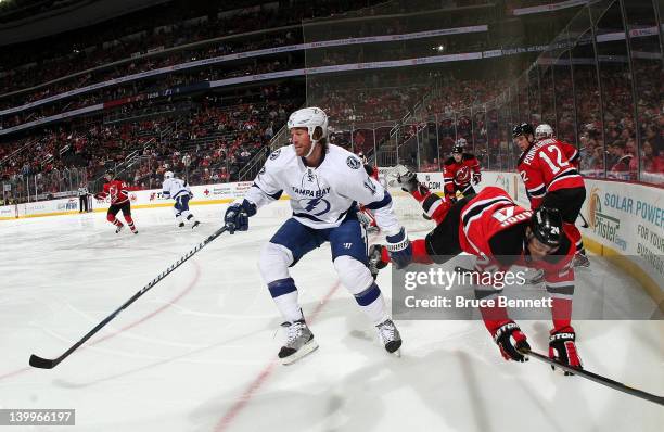 Ryan Malone of the Tampa Bay Lightning knocks Bryce Salvador of the New Jersey Devils off the puck at the Prudential Center on February 26, 2012 in...