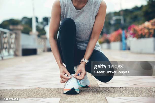 running shoes. woman tying shoe laces. closeup of female sport fitness runner getting ready for jogging outdoors on forest path in late summer or fall. jogging girl exercise motivation heatlh and fitness. - frau gefesselt stock-fotos und bilder