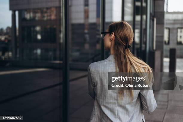 young woman looking into windows reflecting cityscape. - hair clip stock pictures, royalty-free photos & images