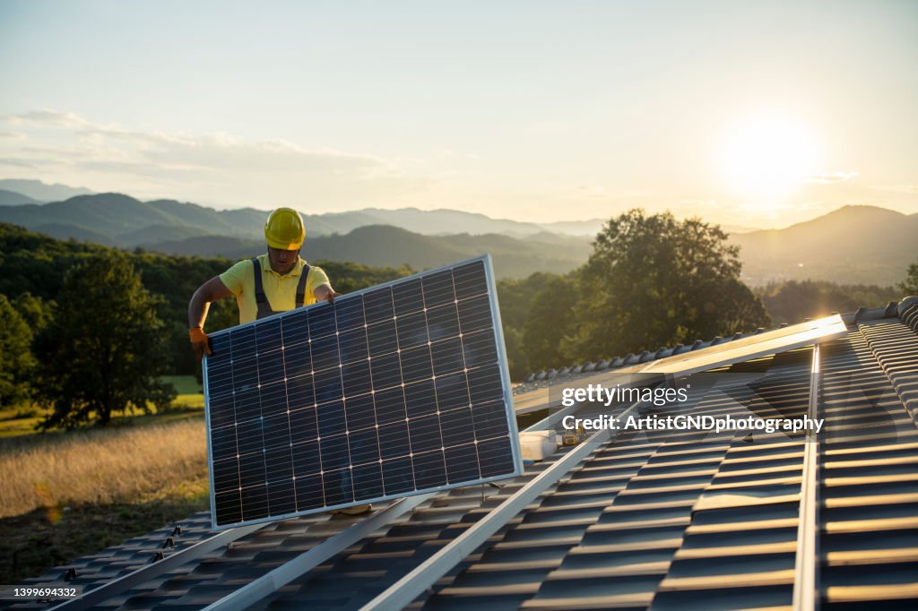 Technicien installant des panneaux solaires sur le toit d’une maison.